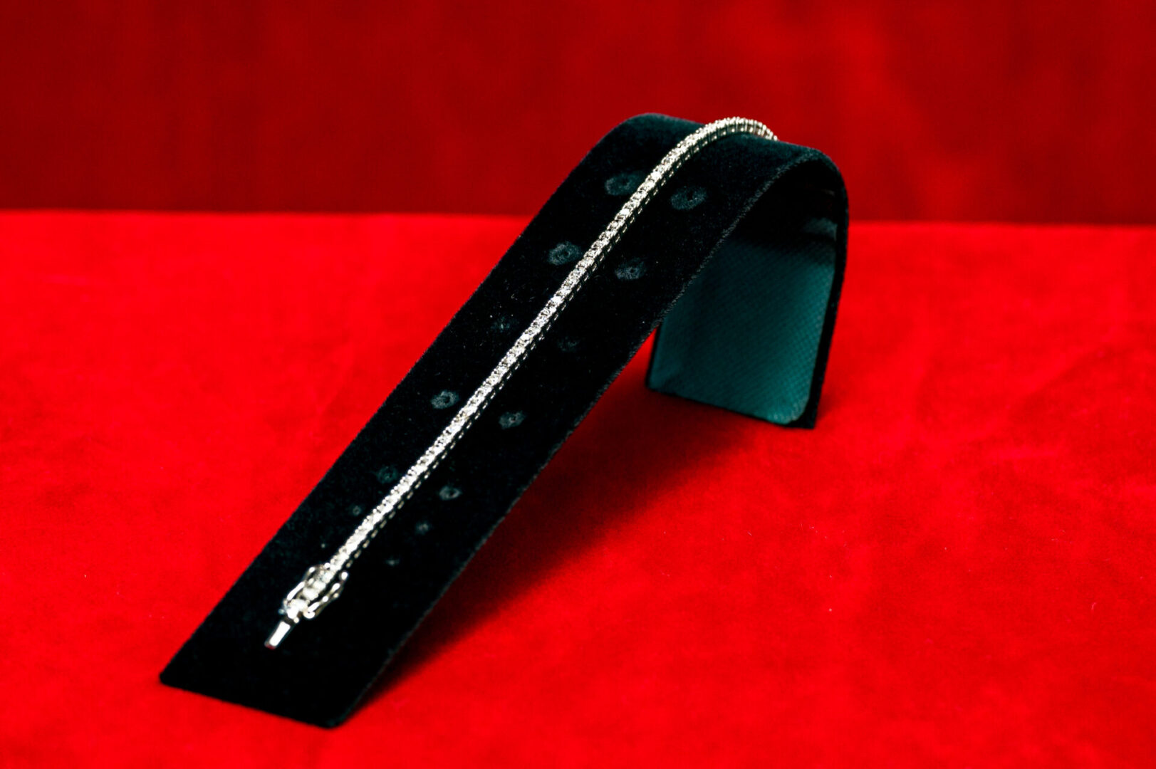 A black bracelet is on top of a red table.