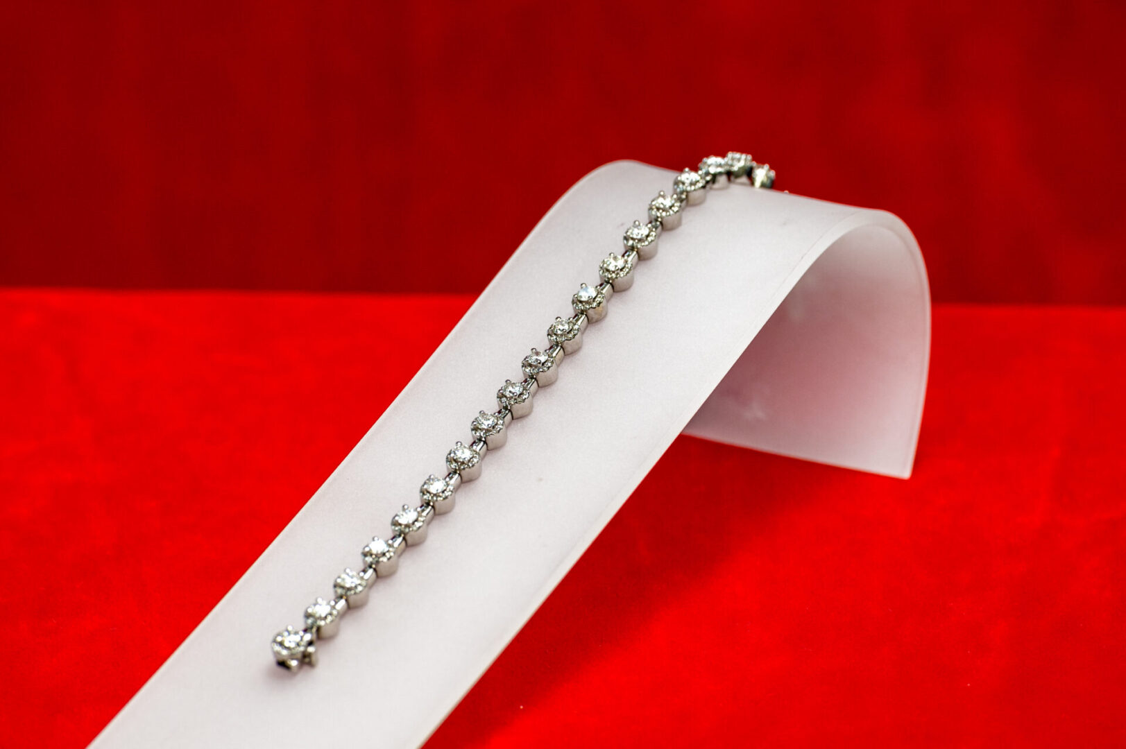 A white bracelet is on top of a red table.