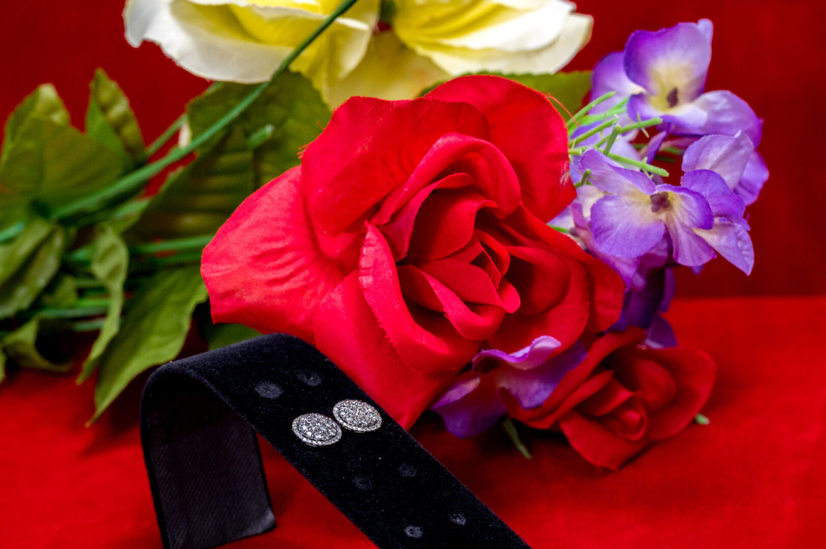 A red rose and some purple flowers on a table.