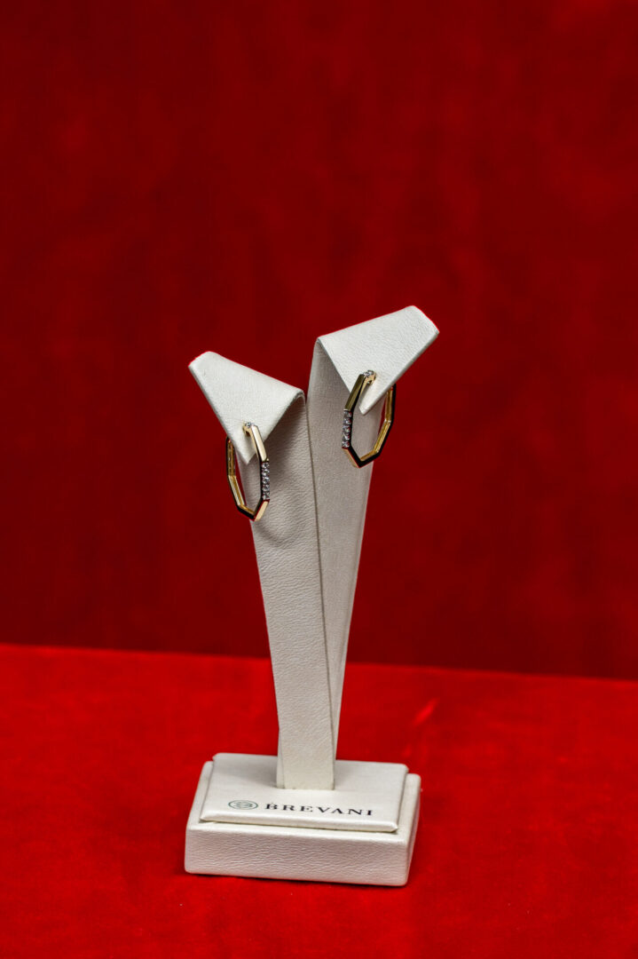 A pair of silver earrings on display in a white holder.